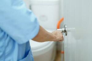 Asian senior woman patient open toilet bathroom by hand in nursing hospital, healthy strong medical. photo