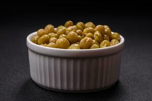 Delicious canned green peas with salt and spices in a white bowl photo