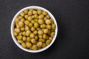 Delicious canned green peas with salt and spices in a white bowl photo