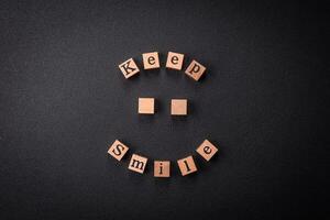 A concept consisting of the inscription of the word smile, with round emoticons on a dark concrete background photo