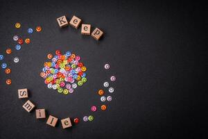 A concept consisting of the inscription of the word smile, with round emoticons on a dark concrete background photo