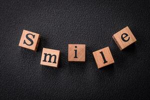 A concept consisting of the inscription of the word smile, with round emoticons on a dark concrete background photo