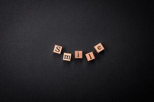 A concept consisting of the inscription of the word smile, with round emoticons on a dark concrete background photo