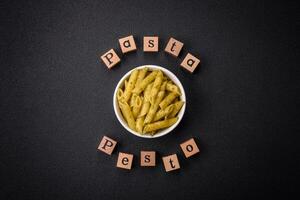 Delicious fresh pasta penne with green pesto sauce with basil, salt and spices photo