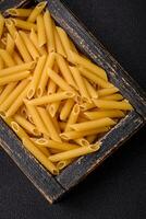 Raw penne pasta from whole grain wheat varieties with salt and spices photo