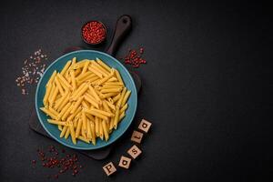 Raw penne pasta from whole grain wheat varieties with salt and spices photo