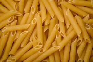 Raw penne pasta from whole grain wheat varieties with salt and spices photo