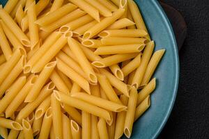 Raw penne pasta from whole grain wheat varieties with salt and spices photo