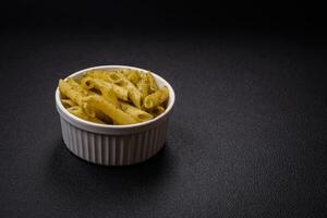 Delicious fresh pasta penne with green pesto sauce with basil, salt and spices photo