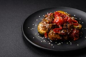 Warm salad with veal, tomatoes, peppers, zucchini, sesame, salt, spices and herbs photo