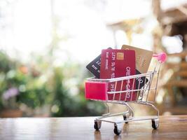 crédito tarjetas en compras carro en el mesa con naturaleza antecedentes. foto