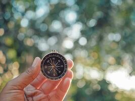 Hand holding compass with nature background. The concept of world tourism day, Searching the right directions and Travel photo