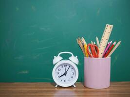 estudiante creativo escritorio con vistoso papelería y blanco alarma. Copiar espacio para texto, espalda a escuela, educación concepto foto