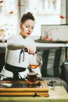 Beautiful girl brews tea for visitors in coffee photo