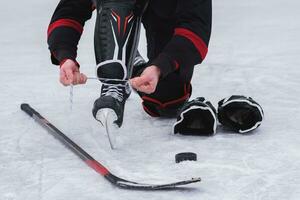 hockey player sitting on the ice to tie shoelaces photo