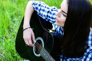 niña en un verde prado jugando guitarra foto