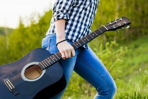 Girl walking in the field with a guitar in hand photo