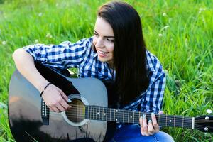 girl on a green meadow playing guitar photo