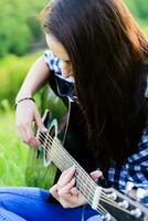 niña en un verde prado jugando guitarra foto