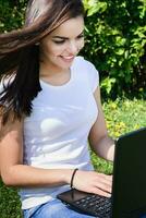 beautiful girl sitting in the park with a laptop photo