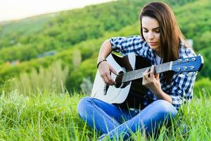 niña en un verde prado jugando guitarra foto