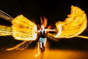 woman juggles with fire in total darkness photo