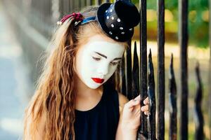 little girl mime is sad standing at the fence photo