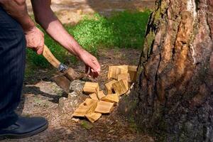 Hands of a man chopping wood with an axe at a picnic photo