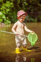 pequeño niño capturas pescado y ranas en el río foto