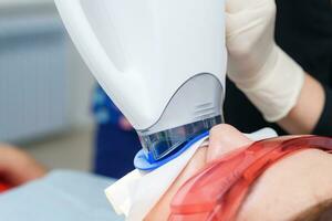 the patient undergoes a procedure for teeth whitening with an ultraviolet lamp photo