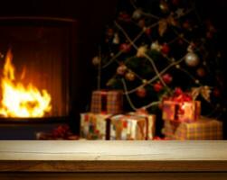 Empty wooden table over defocused Christmas background with Christmas tree, Gifts and fireplace, free space for your decoration. photo