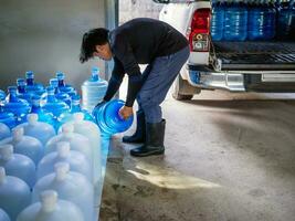 Workers lift drinking water clear and clean in blue plastic gallon into the back of a transport truck purified drinking water inside the production line small business photo