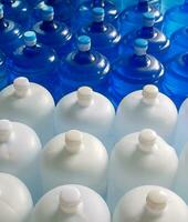 Top view of plastic big bottles or white and blue gallons of purified drinking water inside the production line. Water drink factory photo