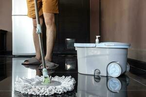 Man mopping floor and mopping bucket on the floor photo