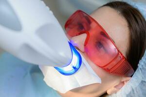 the patient undergoes a procedure for teeth whitening with an ultraviolet lamp photo