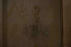 hand marks on a shower screen wet and fogged by the steam of hot water. photo