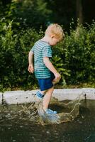 pequeño chico saltando en un charco en verano foto