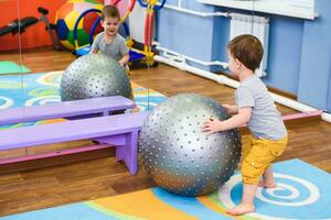 little baby plays with a fitball in the gym photo