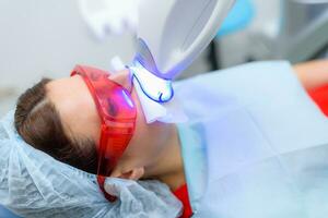 the patient undergoes a procedure for teeth whitening with an ultraviolet lamp photo