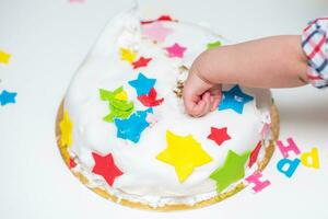 Little baby touches his birthday cake which lies on the table photo