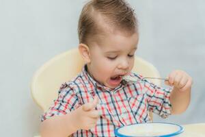 the kid in the kitchen eats milk porridge photo