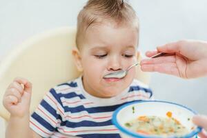 mom feeds her little baby with a spoon photo