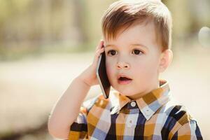 cute boy speaks by mobile phone in the park photo