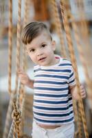 a little boy walks along a stretched wooden bridge in a rope town photo