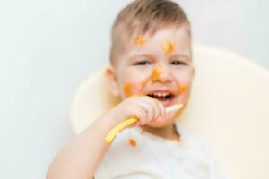 linda bebé chico mientras comiendo manchado su cara con un calabaza foto