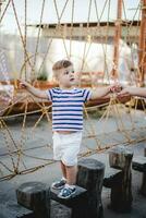 a little boy walks along a stretched wooden bridge in a rope town photo