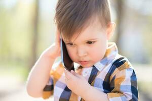 hermosa bebé habla en el teléfono en naturaleza foto