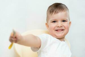 adorable baby boy eats porridge with a small spoon himself photo