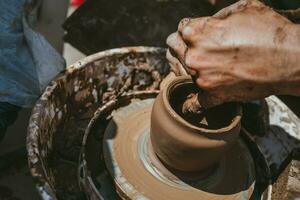 Master hands makes a pot of clay. Master class is held in nature, close-up photo