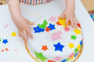 Little baby touches his birthday cake which lies on the table photo